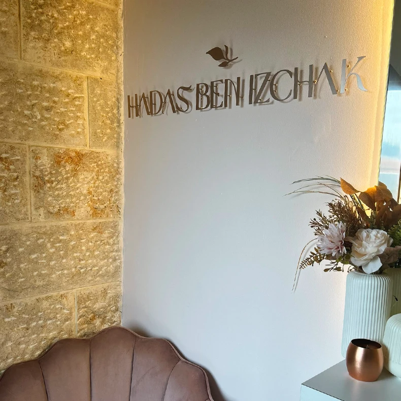 פינת ישיבה בסטודיו עם קיר אבן ושלט HADAS BEN IZCHAK